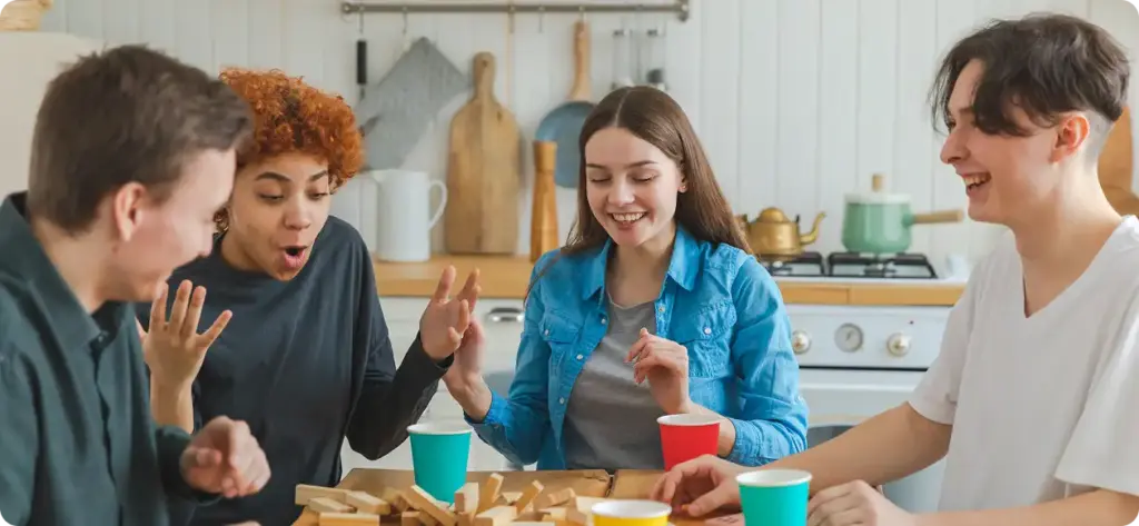 Een groep jonge mensen speelt Jenga in de keuken, iemand heeft verloren.