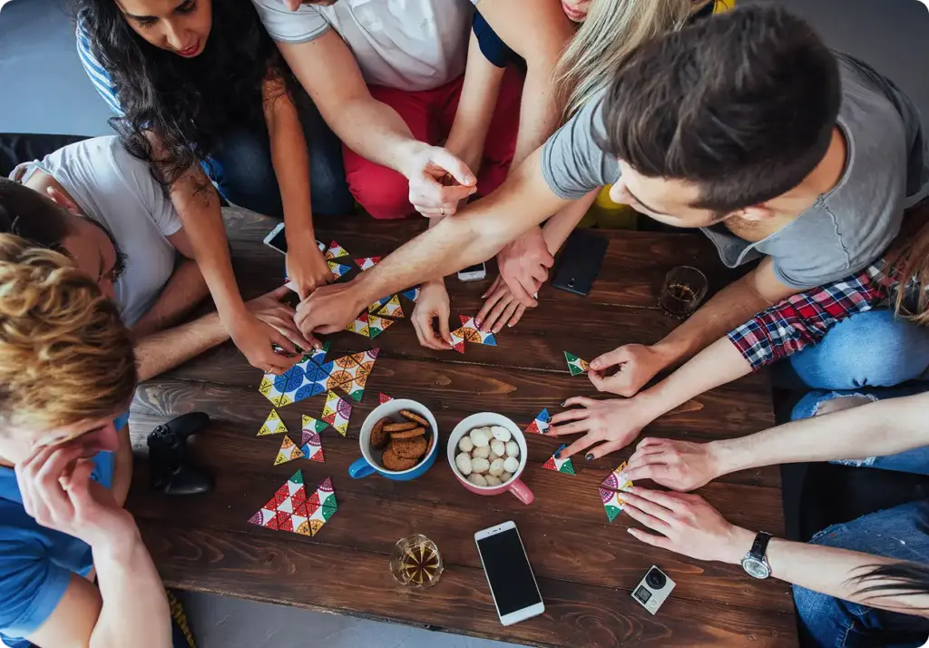 Een groep jonge mensen zit aan tafel en speelt een bordspel.