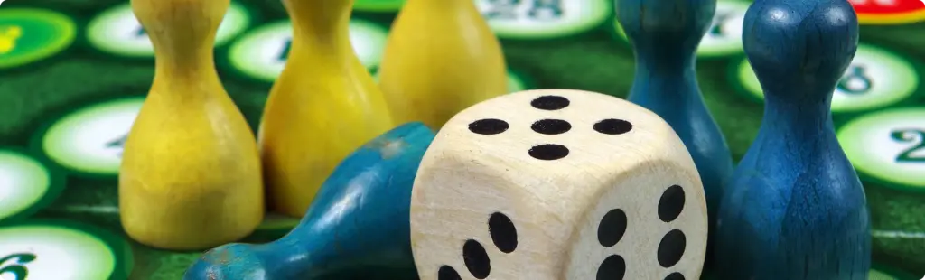 Een houten blokje en gekleurde fiches liggen op het spelbord.