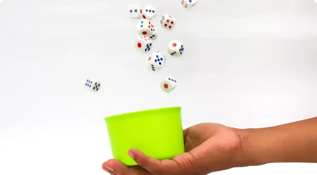 De hand houdt een groen bekertje vast waaruit blokjes vallen.