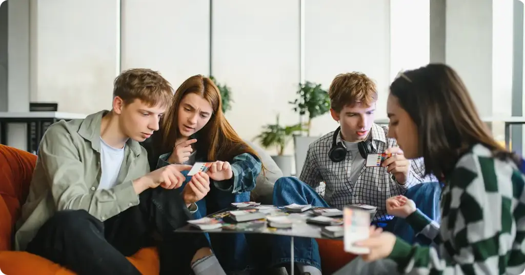 Een groep jonge mensen zit in zachte fauteuils en speelt een bordspel.