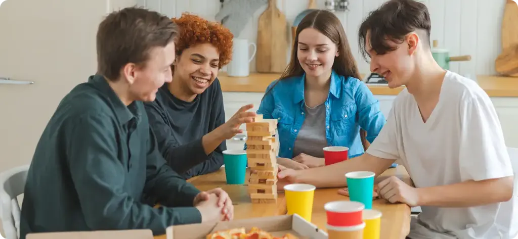 Een groep jonge mensen speelt Jenga aan tafel.